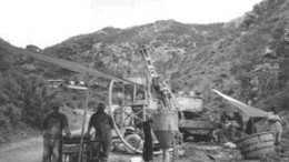 COLOUR PIC -- FPODrillers stand near a reverse-circulation drill on the Dolores Main zone. Another core rig turns on the ridge in the background. The property consists of nine concessions totalling 277 sq. km. Seven of the concessions comprise 19 sq. km covering the core of the Dolores district. Minefinders can purchase a 100% interest in these concessions by paying a total of US$1.5 million at the rate of US$25,000 each quarter. So far, the company has paid US$942,000.