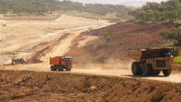 Trucks ferry material to and from the tailings dam construction site.