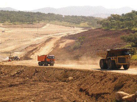 Trucks ferry material to and from the tailings dam construction site.