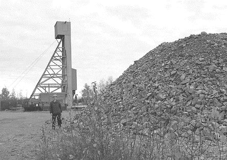 Rosaire Emond, Agnico Eagle's project manager at Goldex, stands beside a bulk sample taken from the Goldex deposit. The Goldex headframe is in the background.