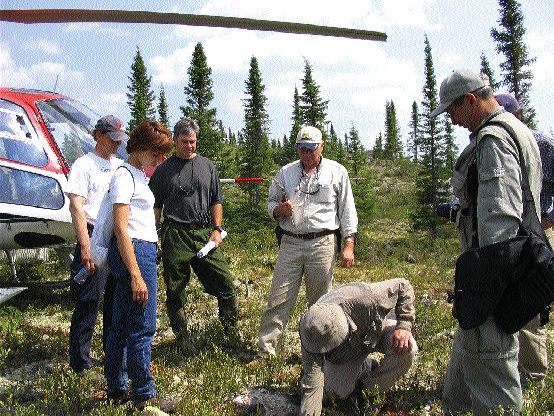 From left: Ashton Project Geologist Alan O'Conner (green pants) and Project Manager Robert Lucas (centre) look on as Pierre Bertrand, vice-president of exploration with Soquem, examines the ground at the Lynx South showing on Ashton's Foxtrot property in north-central Quebec.