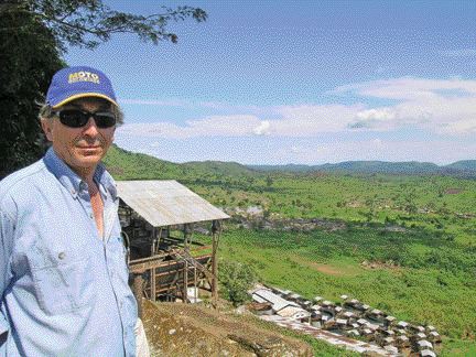 Moto Goldmines project manager Greg Smith stands above a valley surrounding the company's prospective gold property in northeastern Congo. Behind him is a Belgian-built mill near the Durba gold mine, which still operates when there is sufficient feed.