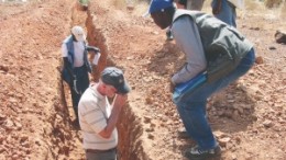 Riverstone Resources' president, Michael McInnis (left foreground), examines rock samples in a trench.