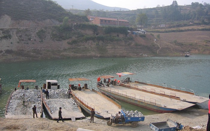 Barges are loaded with ore for transport across the reservoir. Source: Silvercorp Metals