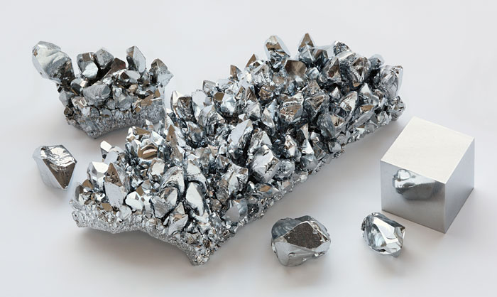 High-purity chromium crystals with a high-purity 1 cm3 chromium cube for scale. Photo by Heinrich Pniok