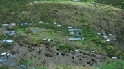 At Minera IRL’s Ollachea gold property in Peru, showing areas mined by local artisanal miners at the bottom. The house near the top with the blue drums is where a second mine portal will be and the flat area is where a tails paste plant will be located. Photo by Paul Harris.