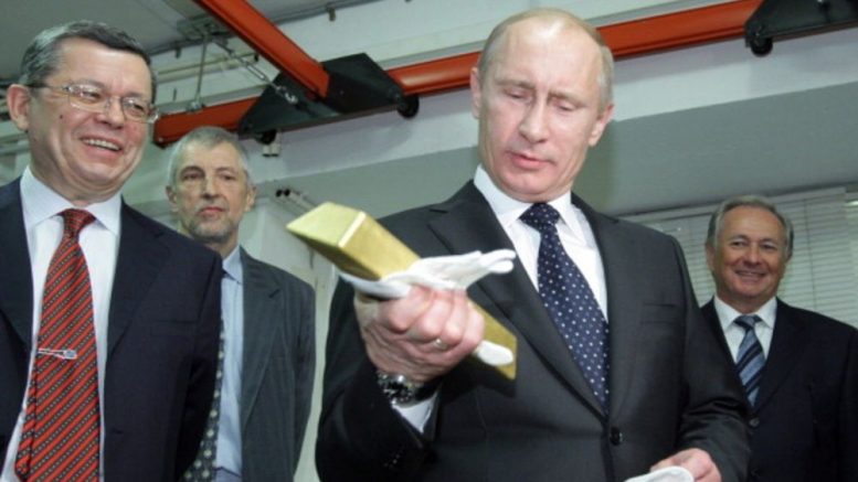 Vladimir Putin, then Russia's prime minister, with a gold bar during a visit in 2011 to the Central Bank of Russia's gold vault. Credit: AFP.
